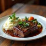 Final presentation of Bear Braised Short Ribs, garnished and served with mashed potatoes and vegetables for a delicious meal.