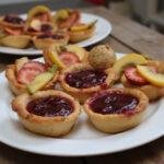 Delicious baked Crown Jam Tarts served on a rustic table, showcasing their vibrant jam filling and artistic presentation.