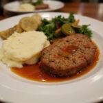 A delicious plate of The Simpsons Meatloaf served with mashed potatoes and vegetables, showcasing a classic comfort food scene.