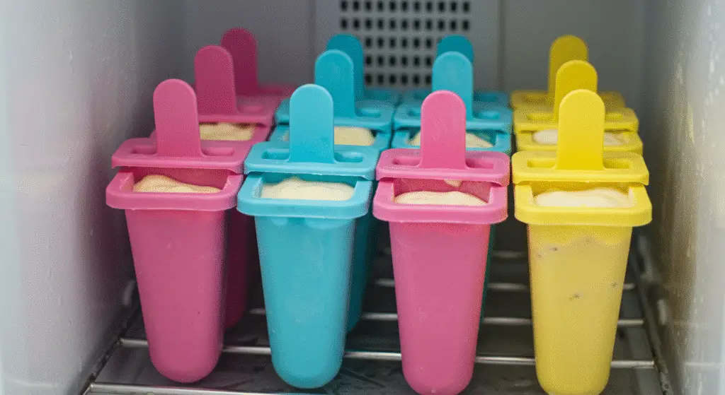 Popsicle molds filled with banana yogurt mixture placed in a freezer to create delicious Arrested Development Frozen Bananas.