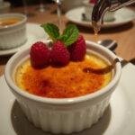 Enjoy the exquisite presentation of Downton Abbey Carson's Ceremonial Crème Brûlée, featuring a perfectly scorched top and decadent garnishes.