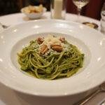 The final presentation of House of Gucci Lady Gaga's Patrizia's Power Pesto Pasta, showcasing the vibrant green pesto and garnishes on a pristine plate.