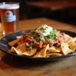 Delicious MacLaren's Pub Nachos served with beer, showcasing a mouthwatering pub dish ready to enjoy.