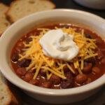Final presentation of How I Met Your Mother Slap Bet Chili, showcasing a hearty dish garnished with cheese and sour cream.