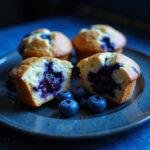 Final presentation of The Matrix Blue Pill Blueberry Muffins, showcasing their moist interior and rich blueberry flavor in a captivating blue setting.
