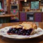 Close-up of Violet Beauregarde's Blueberry Pie displayed on a decorated candy factory kitchen table, showcasing the bright blueberry filling with a shiny glaze, surrounded by colorful candy jars and Willy Wonka-themed decorations, creating an immersive scene inspired by the chocolate factory from the film.