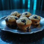 The Matrix Blue Pill Blueberry Muffins arranged on a metallic plate in a dark, futuristic setting with blue glowing accents, inspired by The Matrix.