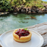 Colorful Moana Heart of Te Fiti fruit tart plated on a rustic wooden surface, topped with vibrant tropical fruits like kiwi, pineapple, and dragon fruit arranged in a flower pattern, with a glossy glaze and edible gold accents, styled with Polynesian-inspired elements.