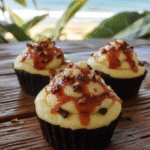 Vibrant cupcakes topped with swirls of pink, purple, and blue frosting resembling a lava flow, adorned with edible glitter and tropical fruit slices, presented on a wooden board with tropical leaves in the background