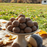 Pastel green and cream-colored choux puffs dusted with toasted grey sesame seeds, arranged on a rustic wooden tray beside a soft plush Totoro figurine and scattered with edible gold flakes under dappled forest-light sunlight. Steam rises gently from the warm puffs, and a drizzle of honey glistens on one split puff, revealing its vanilla custard filling.